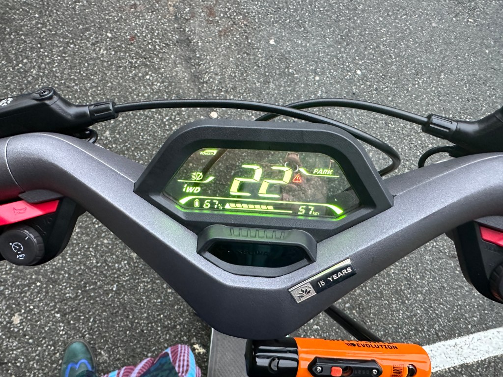 Close-up view of an electric scooter dashboard displaying speed, battery percentage, and distance traveled.