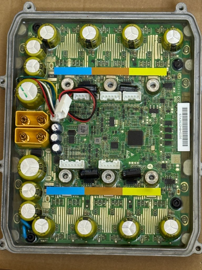 Close-up of an electronic circuit board with capacitors, connectors, and traces, housed in a metal casing.